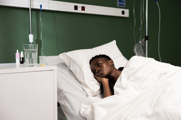 In hospital ward, the young African patient is asleep beimg under medical supervision or recovering from an ailment.