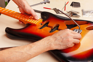 Guitar repairman measures distance of tremolo installation on electric guitar.