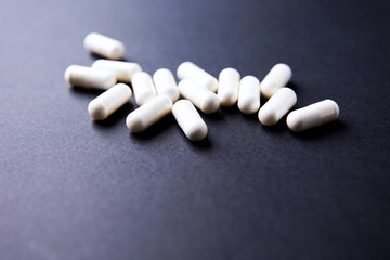 Creatine capsules on dark paper background. Soft focus. Copy space.	