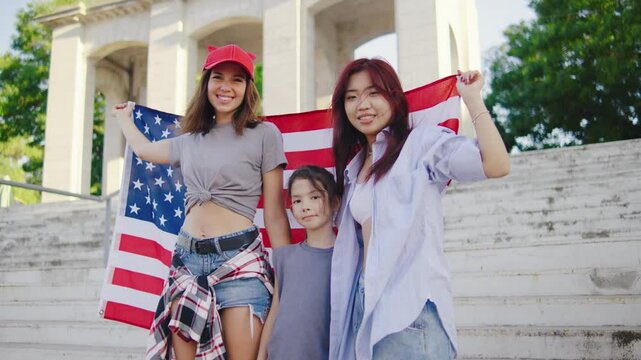 The lesbian family stands together, embracing and wrapping themselves in the U.S. flag. This heartwarming moment symbolizes love, freedom, and unity
