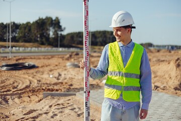 Worker is unfolding leveling rod on construction site.