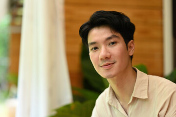 A man looks gently at the camera with a soft, content expression, A Serene Relaxed Moment Indoors