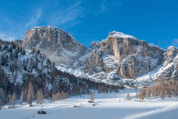 Landscape with a ski slope, forest and mountains covered in snow in the Dolomites in winter