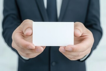 A businessman in a suit holds out his hand with blank white or transparent paper cards for you to copy space text or message on it. 