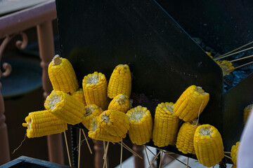 Corn cobs stuck on toothpicks, placed on the grill - wood-fired corn