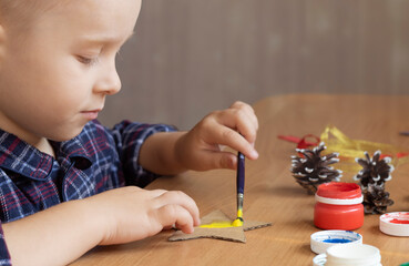 boy making christmas decor. child draws with paints

