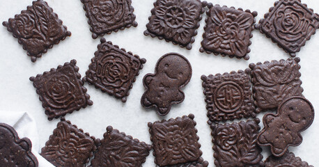 Overhead view of stamped molasses cookies on a parchment lined baking tray, top view of embossed gingerbread cookies on a white background
