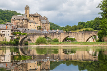 Estaing village, castle and medieval bridge reflecting over Lot river in Aveyron, France