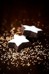 Christmas cookies (cinnamon stars) and brown sugar on dark background. Close up.	