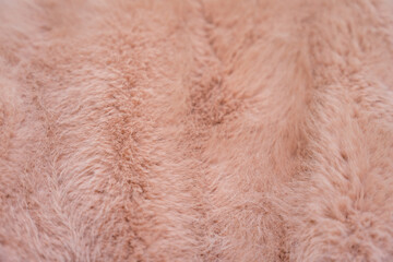 Soft texture of a faux fur coat in warm peach fuzz tones
