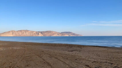 Landscape of sandy beach and quiet clear sea cloudless sky mountains are visible nearby clear morning