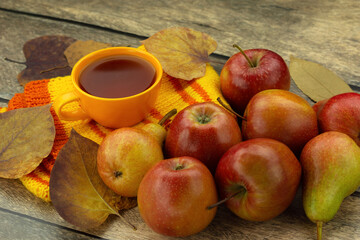 Autumn leaves, tea, scarf and apples on a wooden table. Autumn mood.