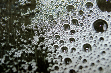 Macro view of bubbles forming on the water surface with dark background