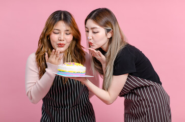 Photo two cute happy fun young Asian beautiful female, woman smiling wearing aprons holding cakes...