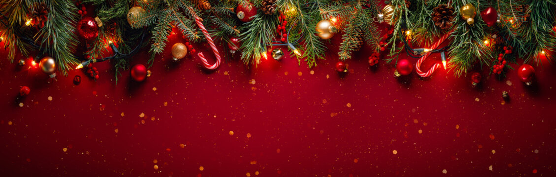 Fir branches with Christmas balls on glittering red background with winter holiday lights