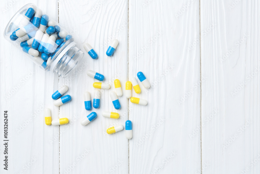 Sticker Pharmacist. Many different pills and overturned bottle on white wooden table, top view. Space for text