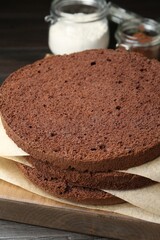 Cut chocolate sponge cake and ingredients on wooden table, closeup