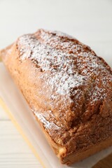 Tasty sponge cake with powdered sugar on white table, closeup