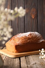 Tasty sponge cake with powdered sugar on wooden table