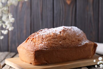 Tasty sponge cake with powdered sugar on table, closeup