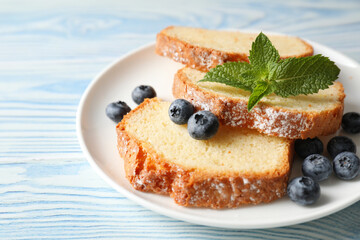 Freshly baked sponge cake, blueberries and mint on light blue wooden table, closeup
