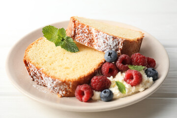 Freshly baked sponge cake, whipped cream, berries and mint on white wooden table, closeup