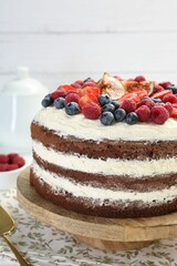 Delicious chocolate sponge cake with berries on table, closeup