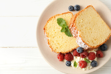 Freshly baked sponge cake, whipped cream, berries and mint on white wooden table, top view. Space for text