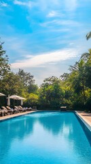 Obraz premium An outdoor swimming pool at a resort hotel, surrounded by sun loungers and lush greenery, with a calm blue sky above, perfect for relaxation