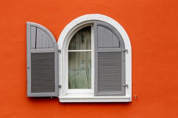 White and grey round window over orange wall