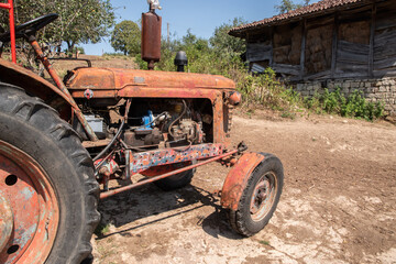 Old weathered grunge vintage tractor on a rural village farm closeup on sunny summer day