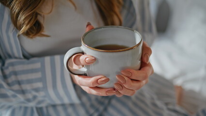 Woman hands holding coffee mug in bedroom closeup. Unrecognizable girl with cup