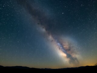 Fototapeta premium A stunning night sky filled with countless stars, the Milky Way glowing brightly across the horizon, and soft silhouettes of mountains in the distance 