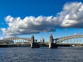 A stunning view of the Peter the Great Bridge, also known as Bolsheokhtinsky Bridge, framed against the backdrop of the iconic Smolny Cathedral in Saint Petersburg. The photograph, captured with a