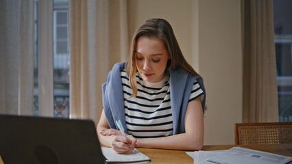 Woman teacher talking online lesson making notes in notebook at home closeup. 