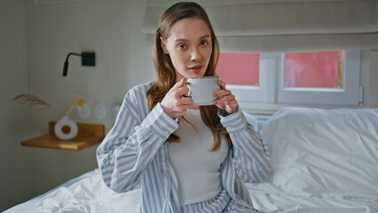 Beautiful girl tasting coffee relaxing on white bedroom closeup. Woman drinking