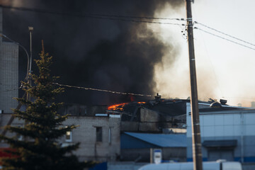 Massive large blaze fire in the city, blazing warehouse factory, storage building is burning, firefighters team putting out the fire, firemen on duty, extinguish the fire, arson, burning house damage
