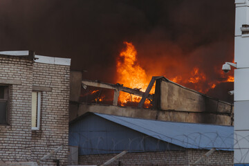 Massive large blaze fire in the city, blazing warehouse factory, storage building is burning,...