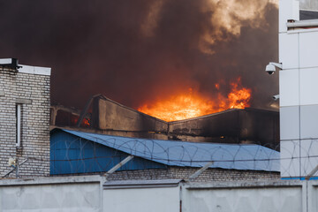 Massive large blaze fire in the city, blazing warehouse factory, storage building is burning,...