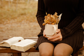 a view of a beige cup with autumn leaves and acorns, which is held by a person.