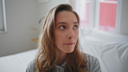 Thoughtful lady sitting bedroom at morning light closeup. Beautiful sad woman