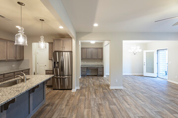 Spacious kitchen featuring granite countertops, stainless steel appliances, and pendant lighting, with an open view of the living area. Investment, renting, or homeownership concept.