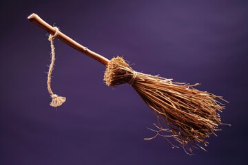 A classic broomstick ornament with a crooked handle and straw bristles, captured in flight against a solid dark purple background, adding a witchy Halloween vibe.