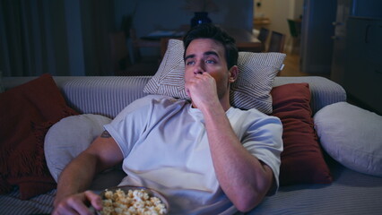 Bored guy watching television in evening living room closeup. Man looking TV