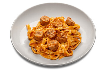 Tagliatelle egg pasta with red tomato sauce with sausage pieces  in white plate isolated