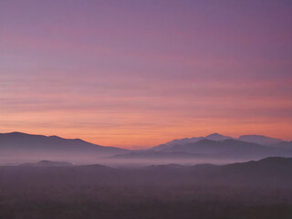The sky at dawn, with a soft gradient of pink, purple, and orange as the first rays of sunlight peek over the horizon

