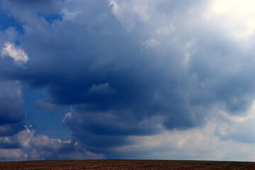 Dunkle Regenwolken am Himmel im Herbst oberhalb eines abgeernteten Feldes bei Konz in...
