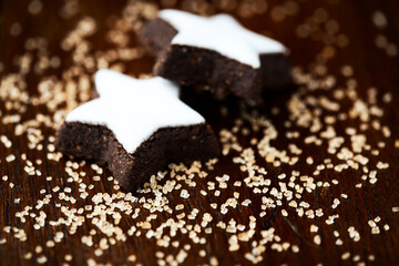 Christmas cookies (cinnamon stars) and brown sugar on dark background. Close up.	