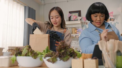Two women working together in a kitchen preparing meals with fresh vegetables and eco-friendly packaging.