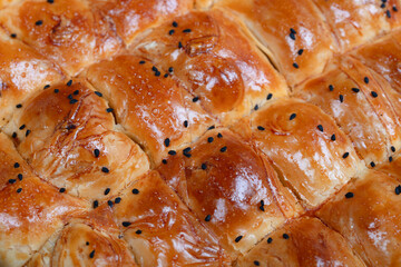 Close-Up of Turkish Cheese Borek with Black Sesame Seeds – Flaky Pastry with Serving Tongs, Ideal for Food Photography and Mediterranean Cuisine Concepts